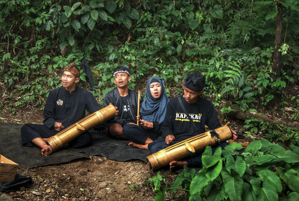 A group of musicians playing bamboo instruments in the lush Indonesian jungle.